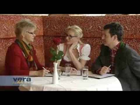 Lehrlingsportal.at Drei Personen sitzen an einem runden Tisch in einem Restaurant und unterhalten sich. Eine Vase mit einer roten Rose und Gläser mit Wasser stehen auf dem Tisch. Das Logo "vera" befindet sich in der linken unteren Ecke.