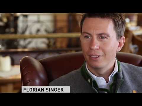 Lehrlingsportal.at Ein Mann in einer grauen traditionellen Jacke sitzt in einem Ledersessel und spricht. Unten links ist der Schriftzug „FLORIAN SINGER.“ eingeblendet.