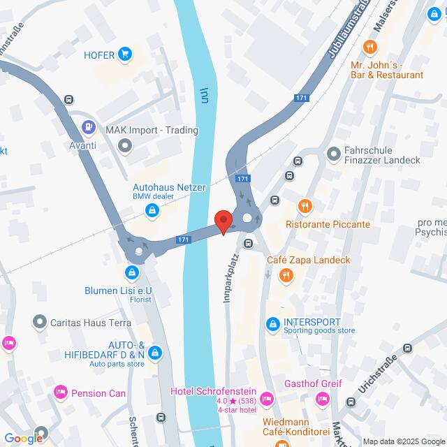 Lehrlingsportal.at Karte mit einem Fluss, der durch eine Stadt fließt, mit Straßen und Kreisverkehren auf beiden Seiten. Zu den nahegelegenen Geschäften gehören ein BMW-Händler, eine Tankstelle, Restaurants und Hotels.