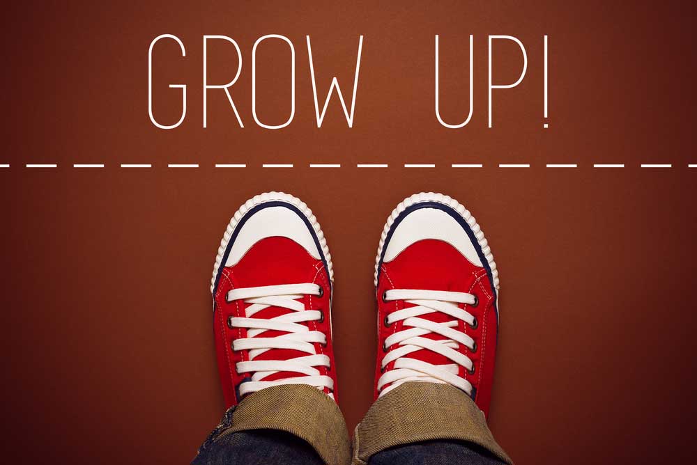 Lehrlingsportal.at Rote Turnschuhe mit weißen Schnürsenkeln auf braunem Hintergrund mit dem Text „GROW UP!“ darüber und einer gestrichelten Linie.