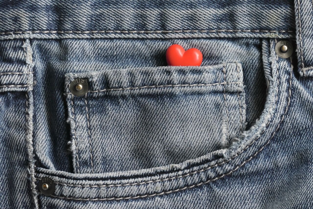 Lehrlingsportal.at Aus der Vordertasche einer Blue-Jeans lugt ein kleines, rotes, herzförmiges Objekt hervor.