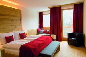 Hotezimmer mit Doppelbett und kleiner Sitzgelegenheit mit Balkon