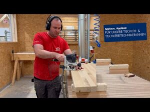 Lehrlingsportal.at Eine Person in einem roten Hemd bearbeitet in einer Werkstatt ein großes Holzbrett mit einer Oberfräse; ein deutscher Text lobt Schreiner und Tischler.