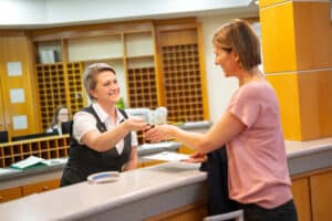 Lehrlingsportal.at Eine Rezeptionistin überreicht einer Frau an der Rezeption eines Hotels eine Schlüsselkarte.