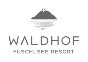 Lehrlingsportal.at Logo mit einem stilisierten Berg und See über dem Text „Waldhof Fuschlsee Resort“ in einem Graustufenfarbschema.