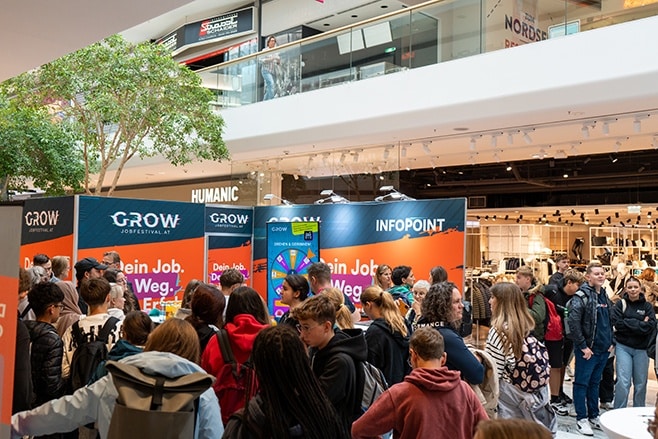 Lehrlingsportal.at Eine Menschenmenge versammelt sich bei einer Jobmesse mit Informationsständen und Beschilderung in einem Einkaufszentrum.