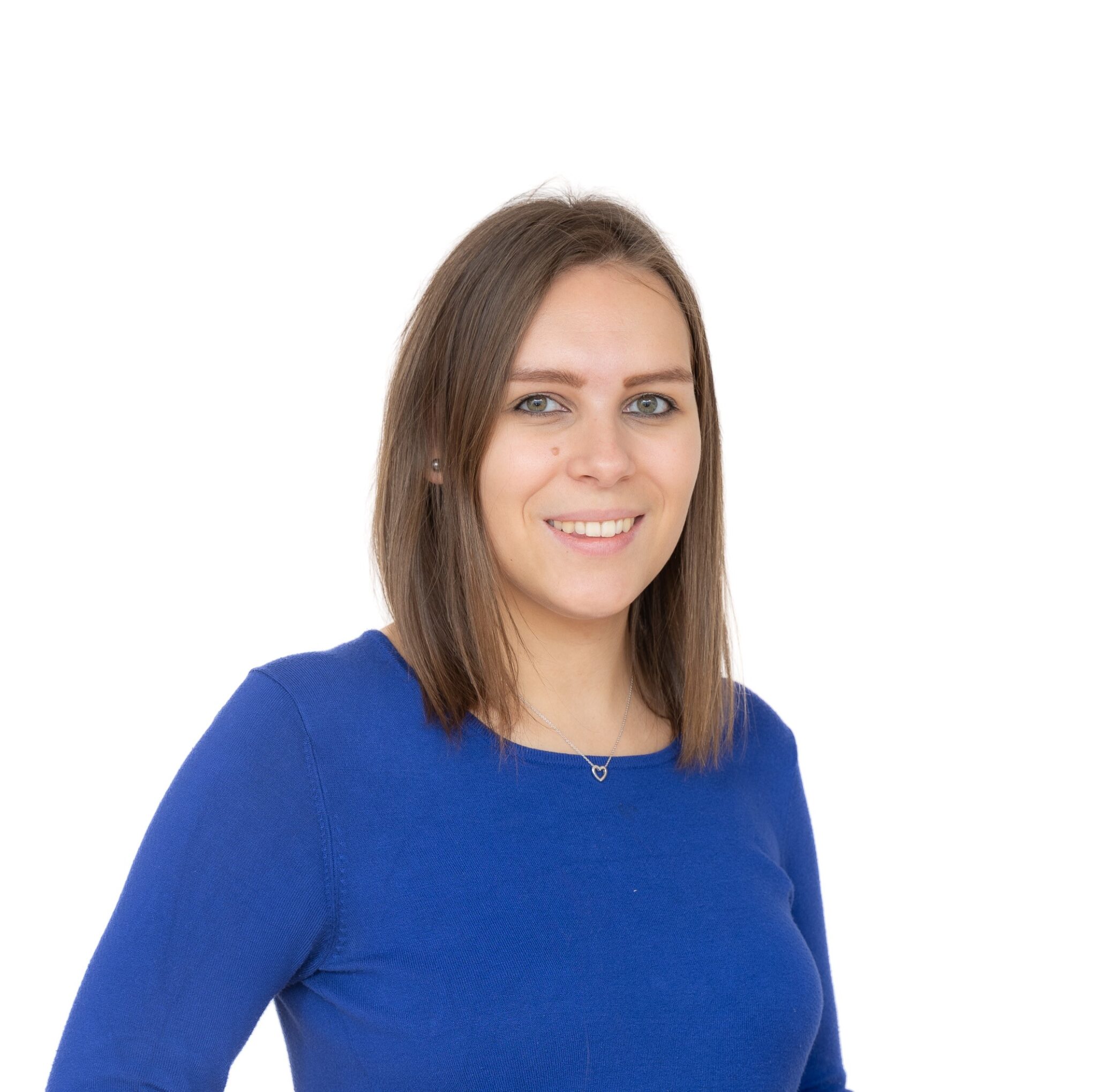Lehrlingsportal.at Eine Frau mit glattem braunem Haar und einem blauen Langarmshirt steht vor einem weißen Hintergrund und lächelt in die Kamera.