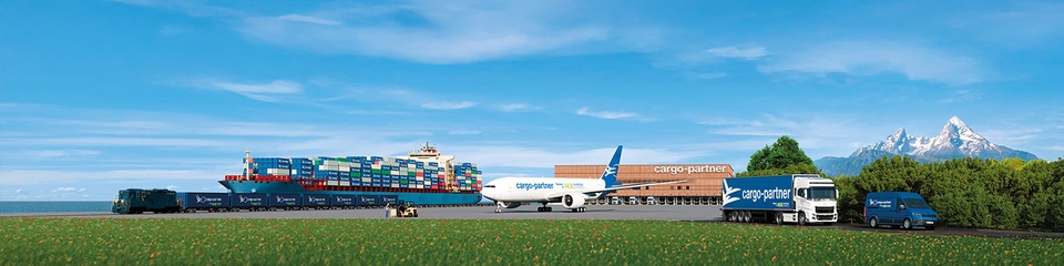 Lehrlingsportal.at Ein Frachtschiff, ein Flugzeug, ein Zug und Lastwagen transportieren Container unter einem blauen Himmel, mit Bergen und Grün im Hintergrund.