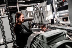 Lehrlingsportal.at Eine Frau bedient und prüft industrielle Schalttafeln und Maschinen in einer technischen oder Produktionsanlage.