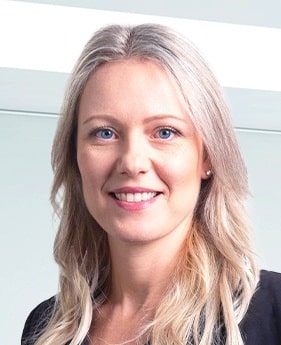 Lehrlingsportal.at Eine Frau mit langen, blonden Haaren und blauen Augen lächelt in die Kamera. Sie trägt ein schwarzes Oberteil und ist vor einem hellen Hintergrund abgebildet.