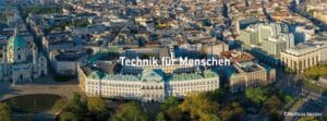 Lehrlingsportal.at Luftaufnahme einer Stadtlandschaft mit historischen und modernen Gebäuden; in der Mitte erscheint der deutsche Text "Technik für Menschen".