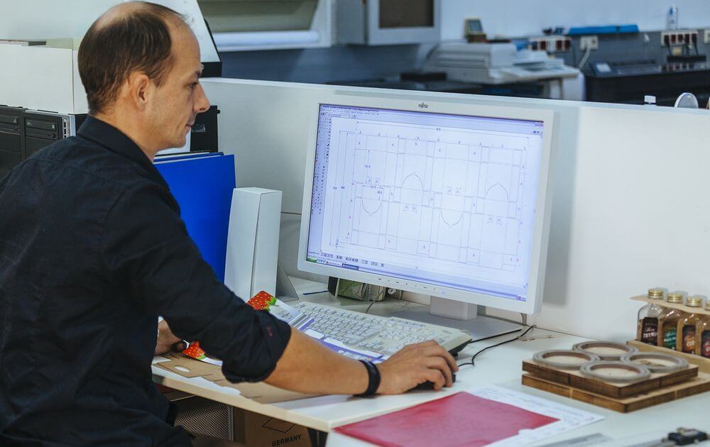 Druckerei Boesmueller Mitarbeiter Sitzt Vor Computer Prueft Plan Ergebnis