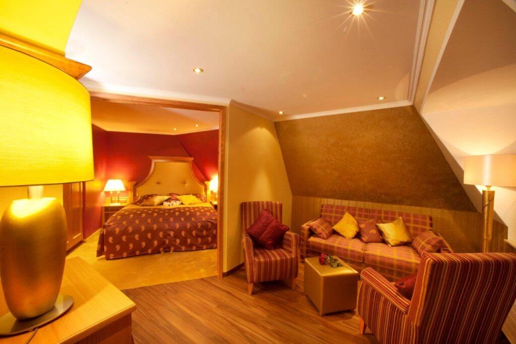 Suite mit Doppelbett und rot-goldener Sitzecke