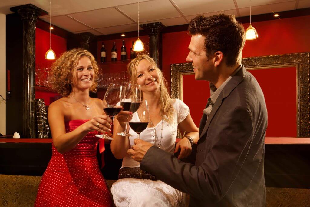 Hotelgäste stoßen mit einem Glas Rotwein in der Cocktailbar an