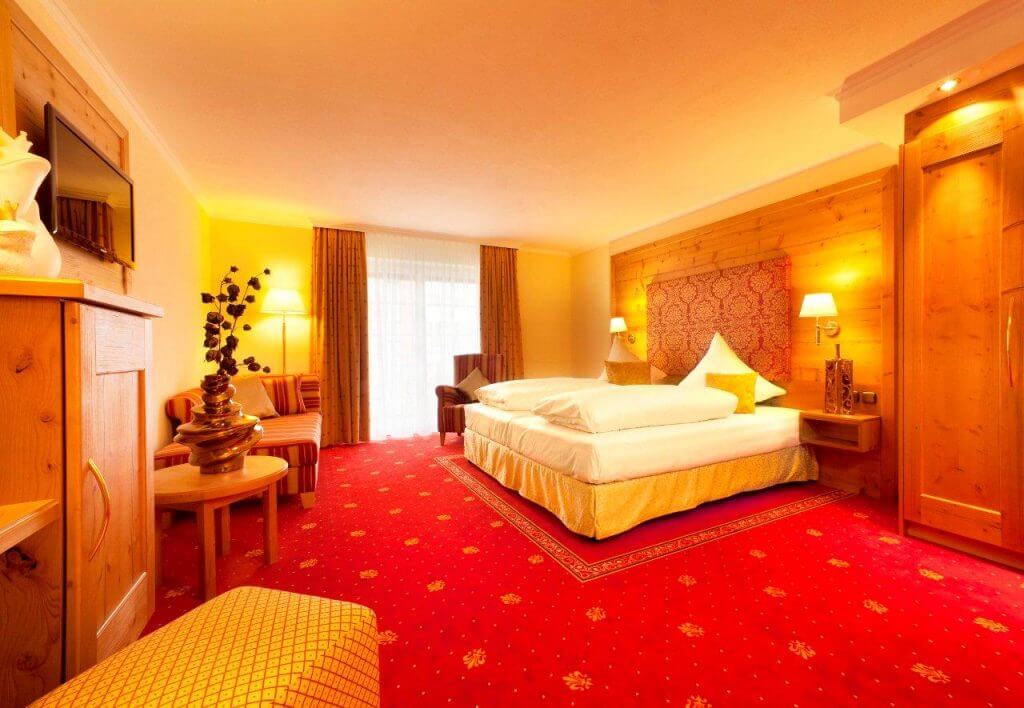 Hotelzimmer mit Kingsizebed und rotem Teppich