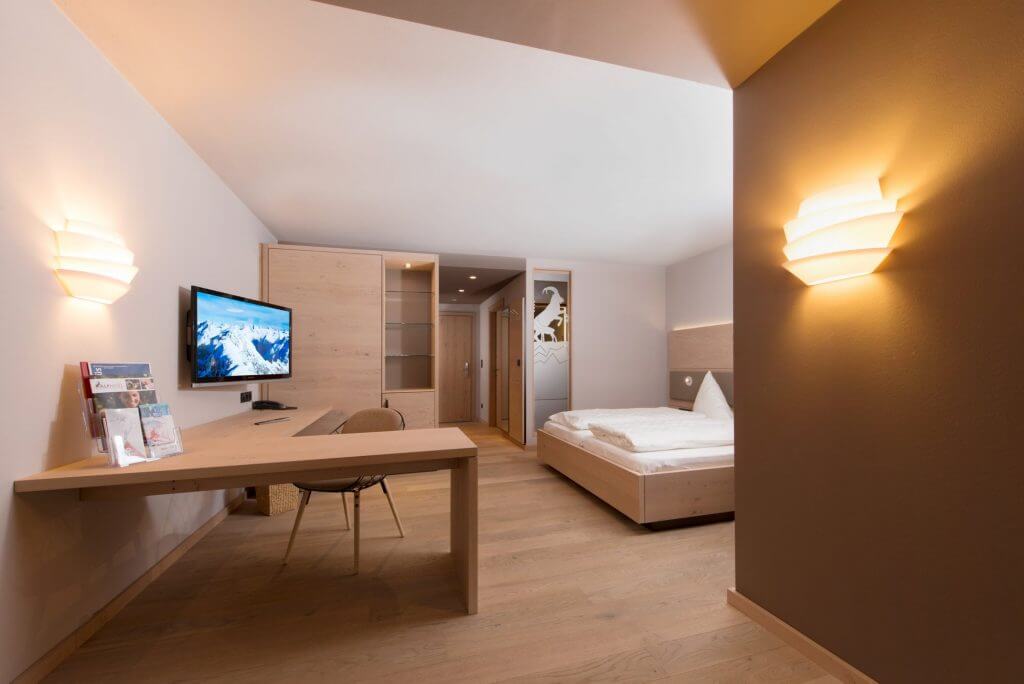 Hotelzimmer mit Doppelbett, Schreibtisch und TV