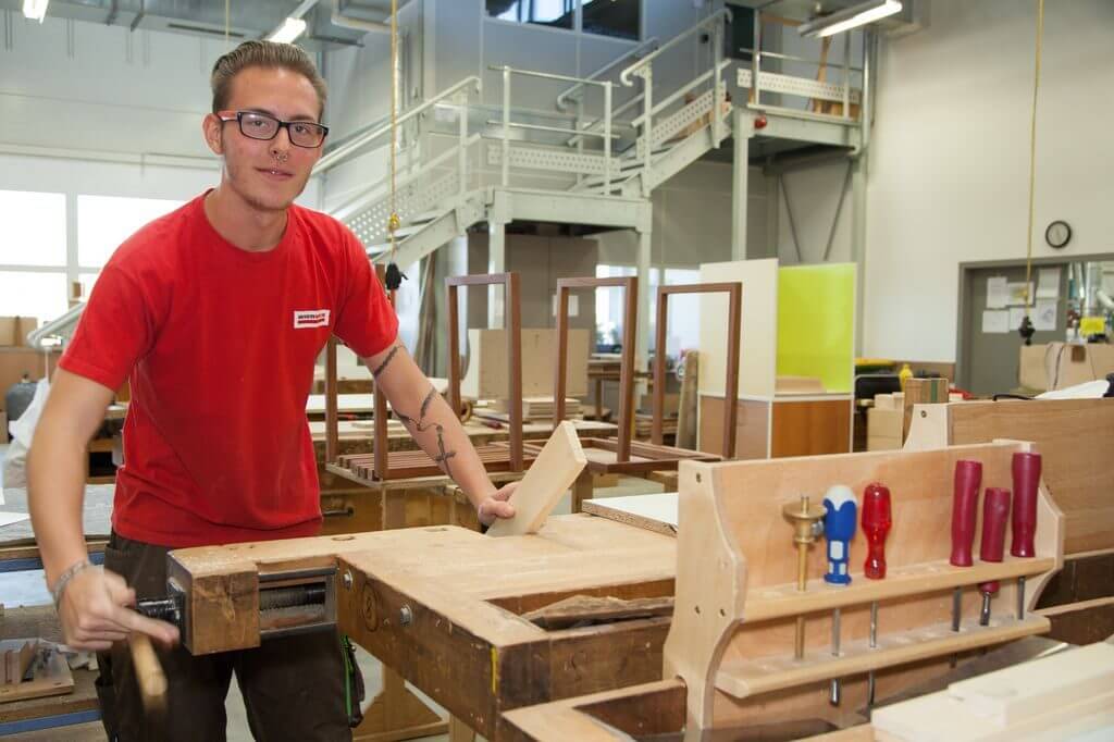 Lehrling arbeitet mit Holz an Werkbank