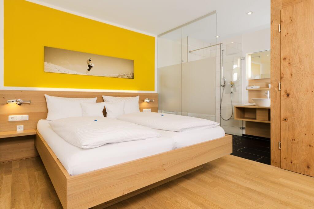 Hotelzimmer mit Doppelbett und gelber Wand