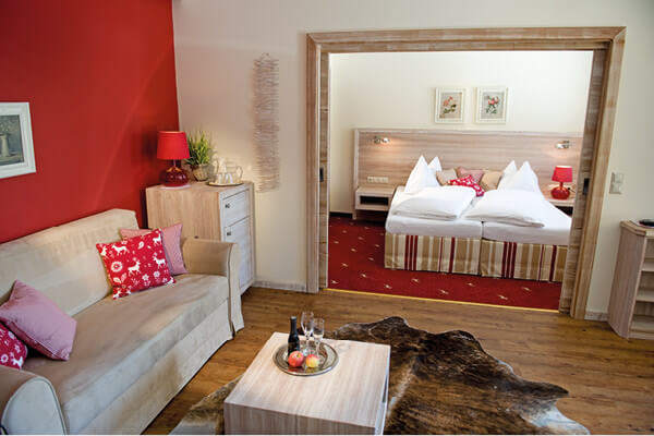 Hotelzimmer mit Sicht auf Doppelbett und gemütlichem Sofa