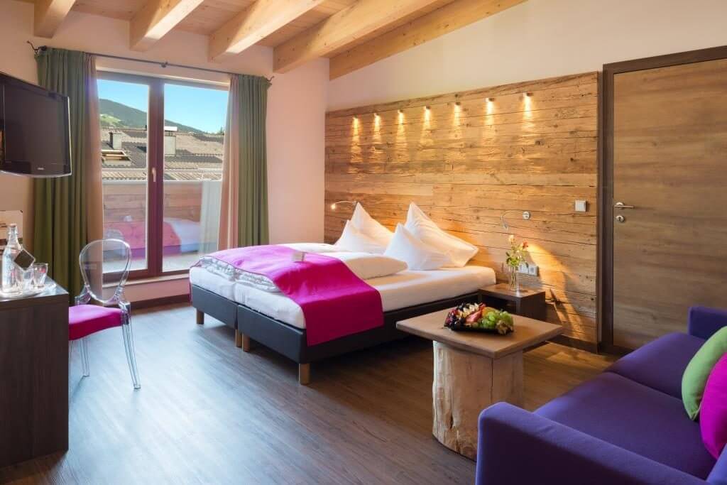 modernes Hotelzimmer mit Doppelbett und lila Sofa
