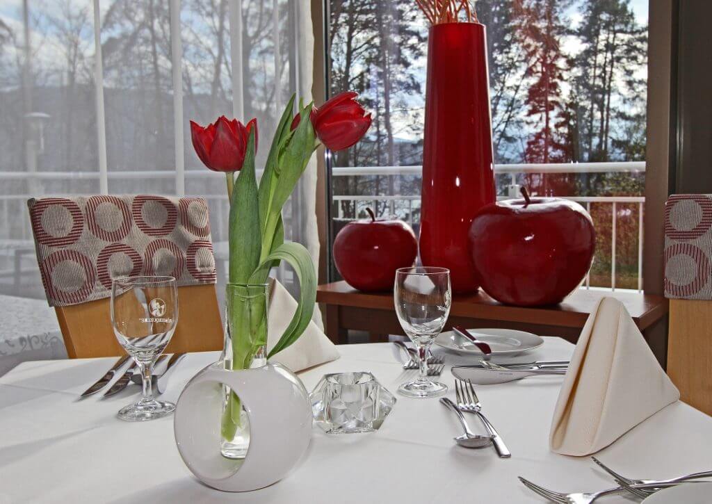 gedeckter Tisch mit roten Tulpen und roten Vasen