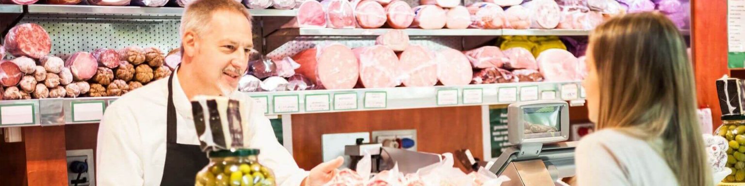 Fleischverkäufer berät Mädchen an der Wursttheke