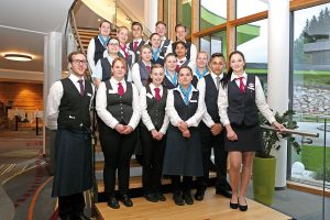 Gruppenfoto aller Vivea Service Lehrlinge in Uniformen auf Treppen